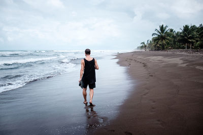 Full length rear view of man walking at beach