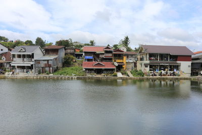 Buildings by river against sky