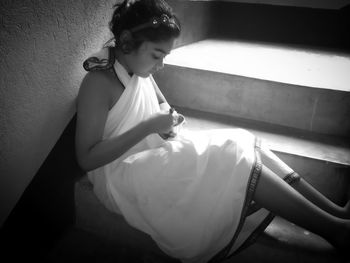 Young woman looking down while sitting on wall at home