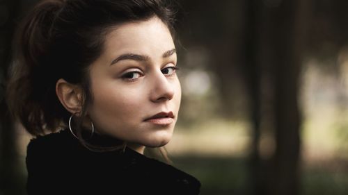 Close-up side view portrait of beautiful young woman outdoors