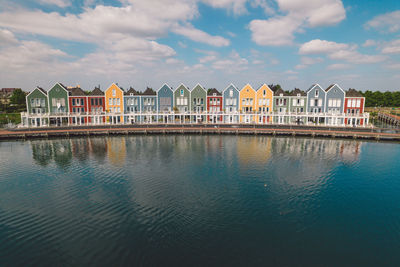 Buildings by river against sky