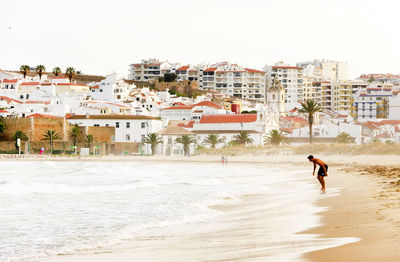 People walking on beach with buildings in background
