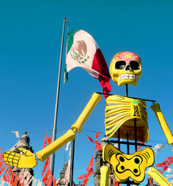 Low angle view of flags against clear blue sky