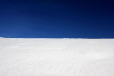 Scenic view of snow covered field against clear blue sky