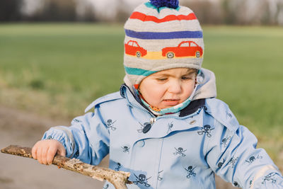 Cute baby girl wearing warm clothing standing in park