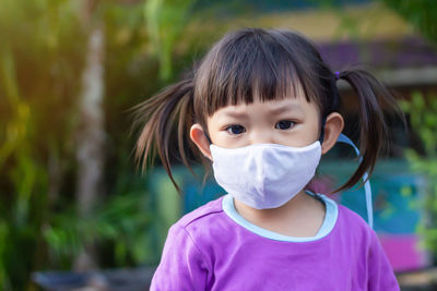 Close-up portrait of girl wearing mask standing outdoors