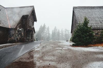 Road amidst buildings against sky during rainy season