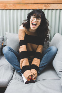 Young woman sitting on sofa at home