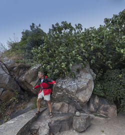 Full length of woman standing on rock against trees