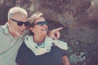 Smiling senior couple standing by rock formation