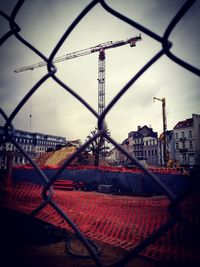 Close-up of cityscape seen through chainlink fence