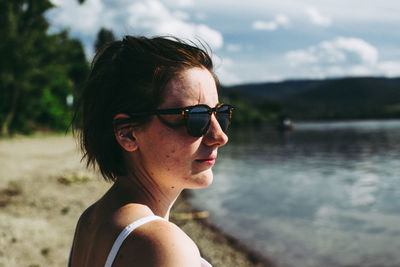 Side view of woman wearing sunglasses looking at lake