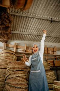 Rear view of woman with arms raised standing against wall