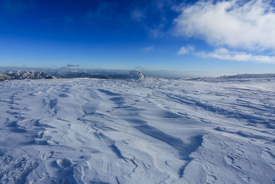 Snow covered landscape against blue sky