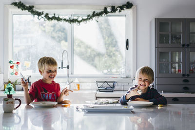 Happy brothers having dessert at table during christmas at home