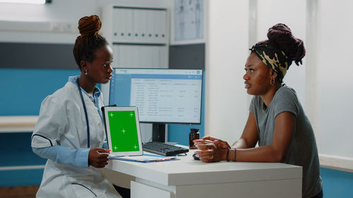 Doctor showing digital tablet to patient in clinic