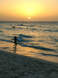 Silhouette man walking on beach against sky during sunset