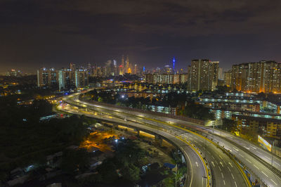 High angle view of illuminated street amidst buildings in city at night