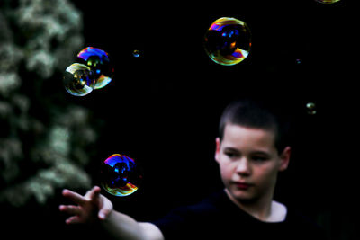 Boy touching bubbles while standing at park