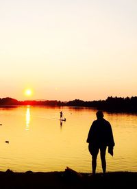 Silhouette of people in lake at sunset