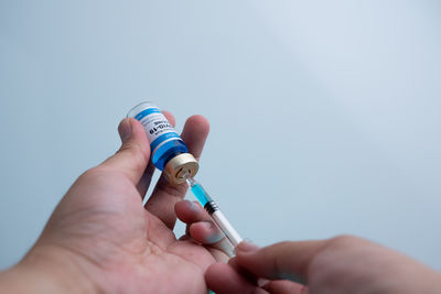 Close-up of hand holding hands against blue wall