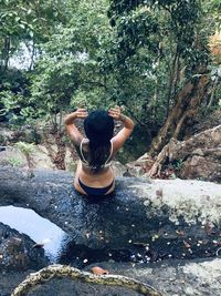 Rear view of woman sitting on rock