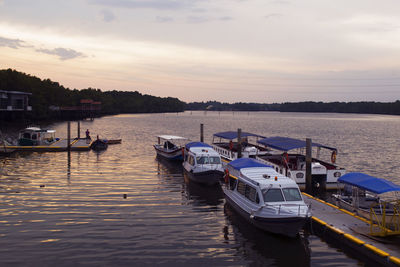 Boats moored on river against sky during sunset