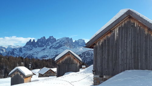 Houses on snow covered field against clear sky