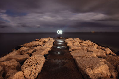 Scenic view of rocks by sea against sky