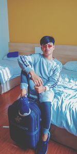 Portrait of boy sitting on bed at home