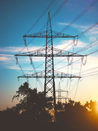 Low angle view of silhouette electricity pylon against sky during sunset