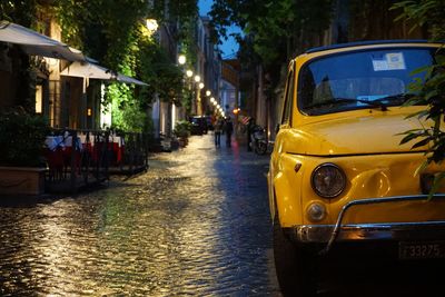 Yellow car on wet road during dusk