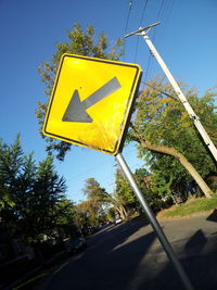 Low angle view of road sign against clear blue sky