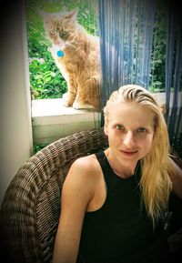 Portrait of smiling young woman with cat sitting at home