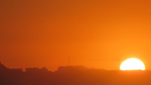 Scenic view of silhouette landscape against orange sky