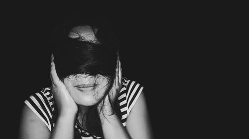 Portrait of teenage girl against black background