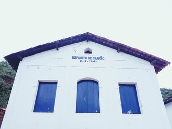 Low angle view of text on building against clear sky