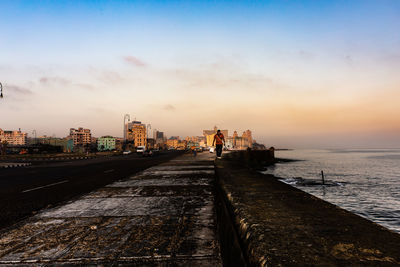 Scenic view of sea by buildings against sky during sunset