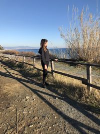 Full length of woman standing by railing against clear sky