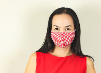 Portrait of woman covering face against wall