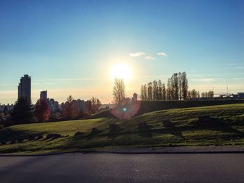 Road by field against sky during sunset