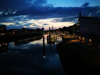 River by illuminated city against sky at dusk