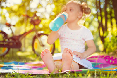 Cute girl drinking water sitting at park