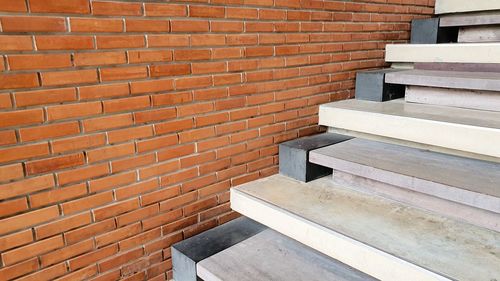 Stack of books on bench against brick wall