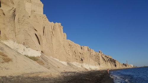 Scenic view of cliff against clear blue sky
