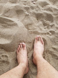 Low section of person standing on sand