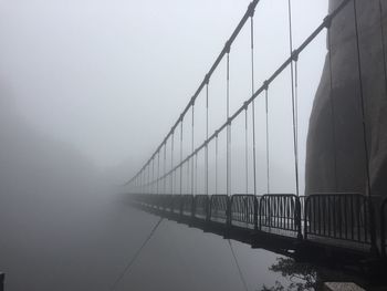 Bridge over river in foggy weather against sky