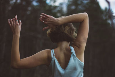 Rear view of young woman dancing in forest