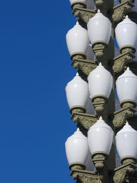 Low angle view of electric lamp against blue sky