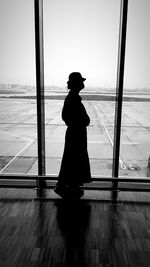 Silhouette woman standing at airport against sky